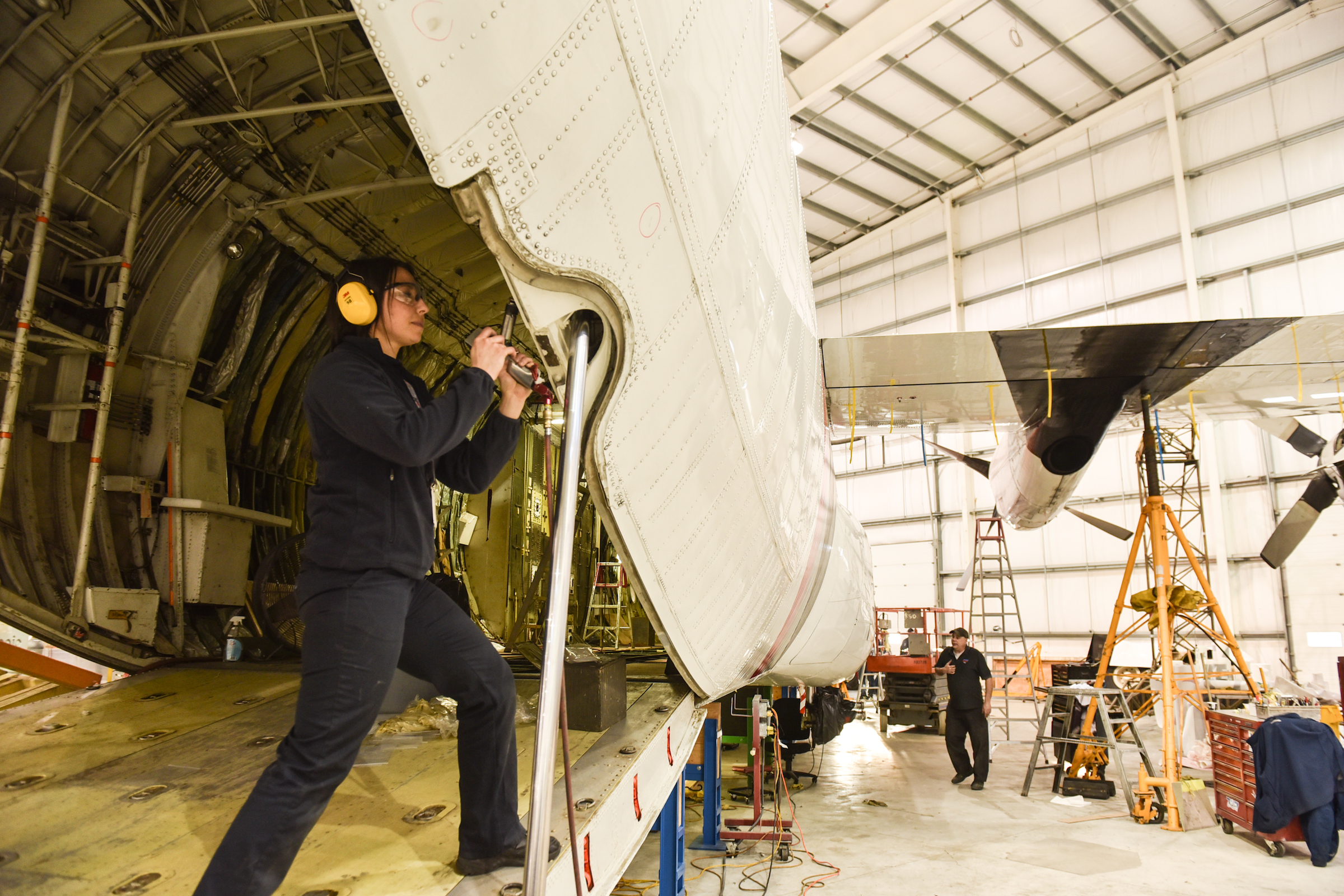 Woman working on the interior of an airplane in a hangar