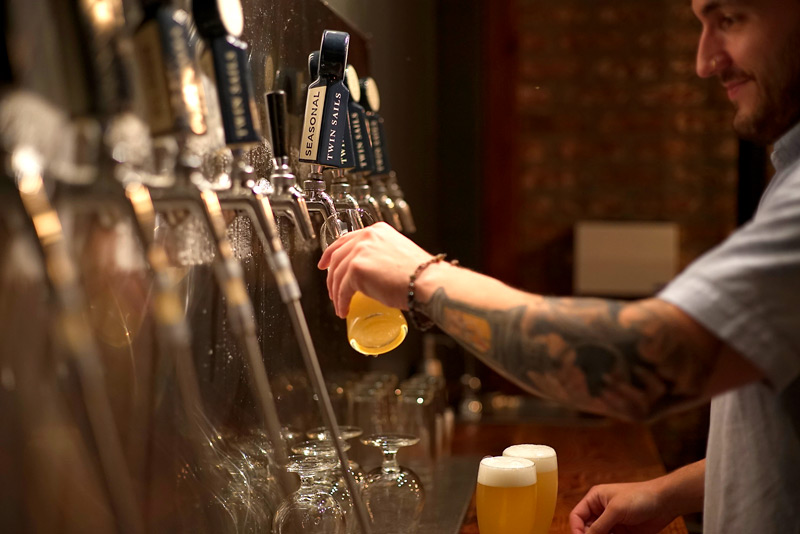 Bartender pouring beer from taps behind a bar