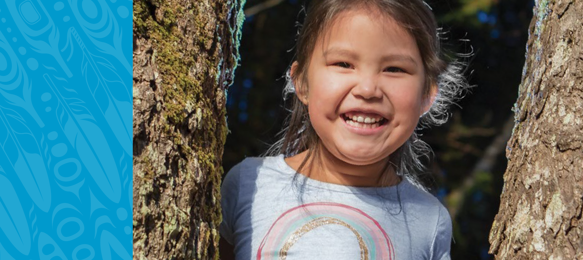 Smiling Indigenous child standing between two trees