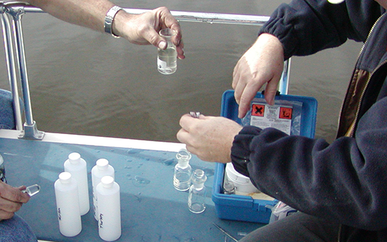Volunteers collecting water samples on a boat