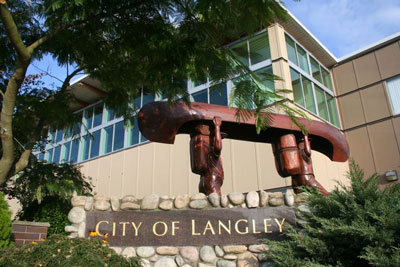 Exterior of Langley library and city hall with wooden carving of two people carrying a canoe