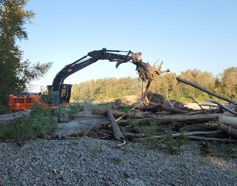 An excavator is used to remove woody debris along the Fraser River
