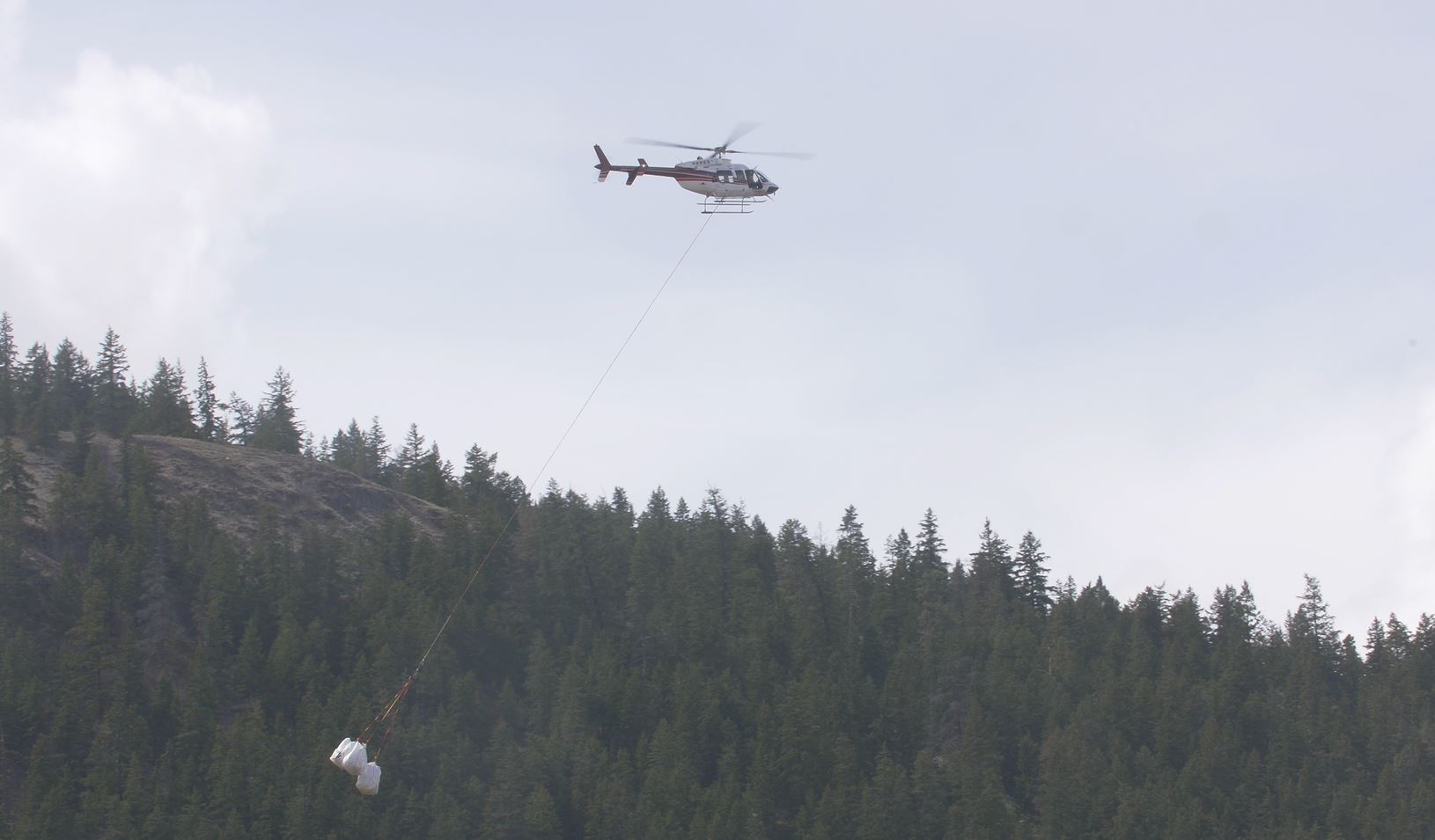 A helicopter removes bags of small woody debris from waterway