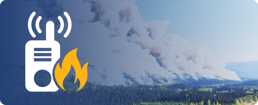 Handheld radio with dense smoke above a forest fire in the background.