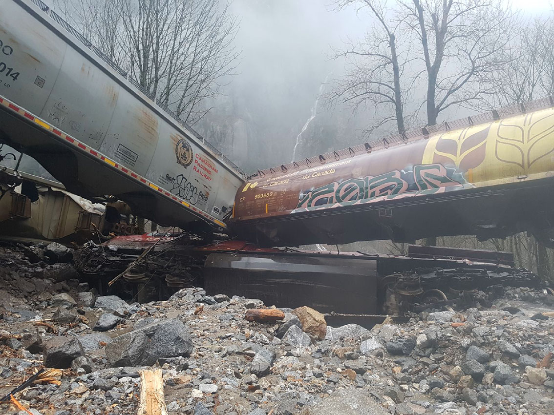A rock slide caused a CP Rail train to derail. This picture shows two empty grain train cars on top of the CP Rail train engine car buried in rocks
