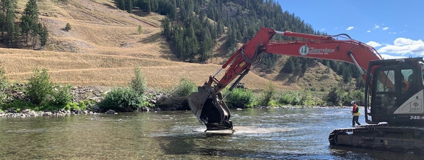 Excavator removing debris from the middle of the river