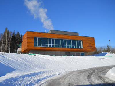 Image of the University of B.C.'s clean energy building on a snowy hill with white smoke puffing from the top