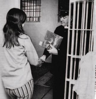 Salvation Army Captain Bob Wilson hands female inmate a Christmas gift (December 23, 1975)