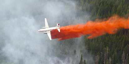 Aircraft dropping fire retardant on a fire.
