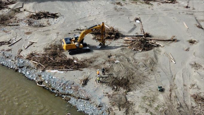 Excavator removes debris along riverbank