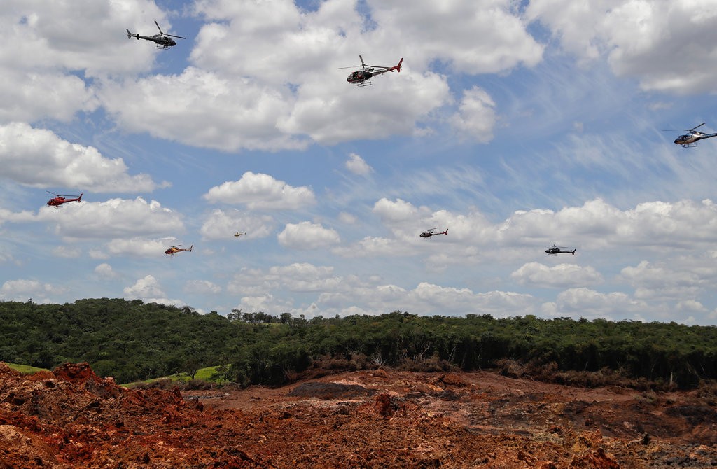 Multiple helicopters searching for survivors amidst areas flooded with mud and debris