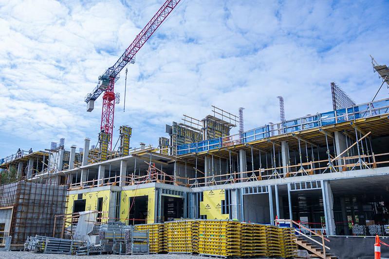 Construction site with crane and multi-story building framework under blue sky. Construction site with crane and multi-story building framework under blue sky.