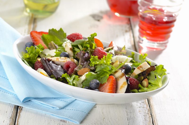 Fresh mixed green salad with grilled chicken, berries, and nuts in a white bowl. Fresh mixed green salad with grilled chicken, berries, and nuts in a white bowl.