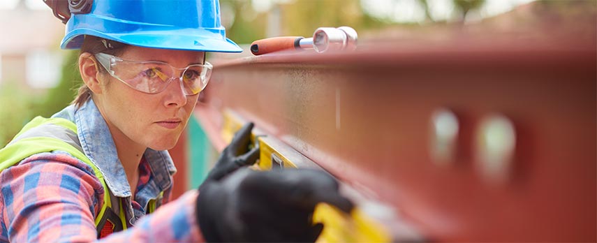 Female construction worker examining steel beam at eye-level