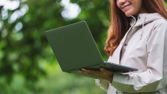 A woman holds an open laptop