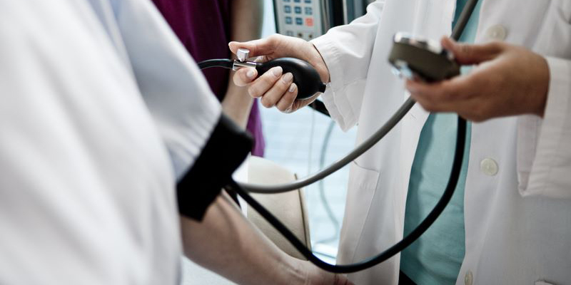 A doctor checking a patients blood pressure.