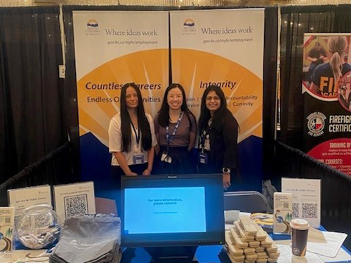 Three BC Public Service employees standing behind a recruitment table.