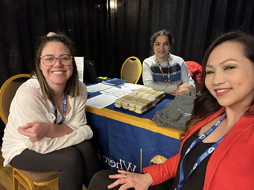 Three people sit at a recruitment table