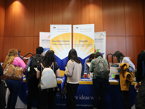 Group of people standing in front of BC Public Service recruitment table.