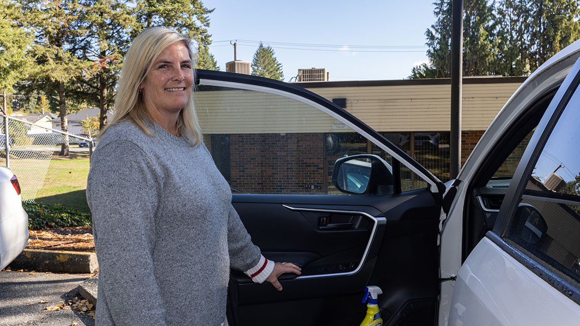 Person with long blonde hair standing by an open car door