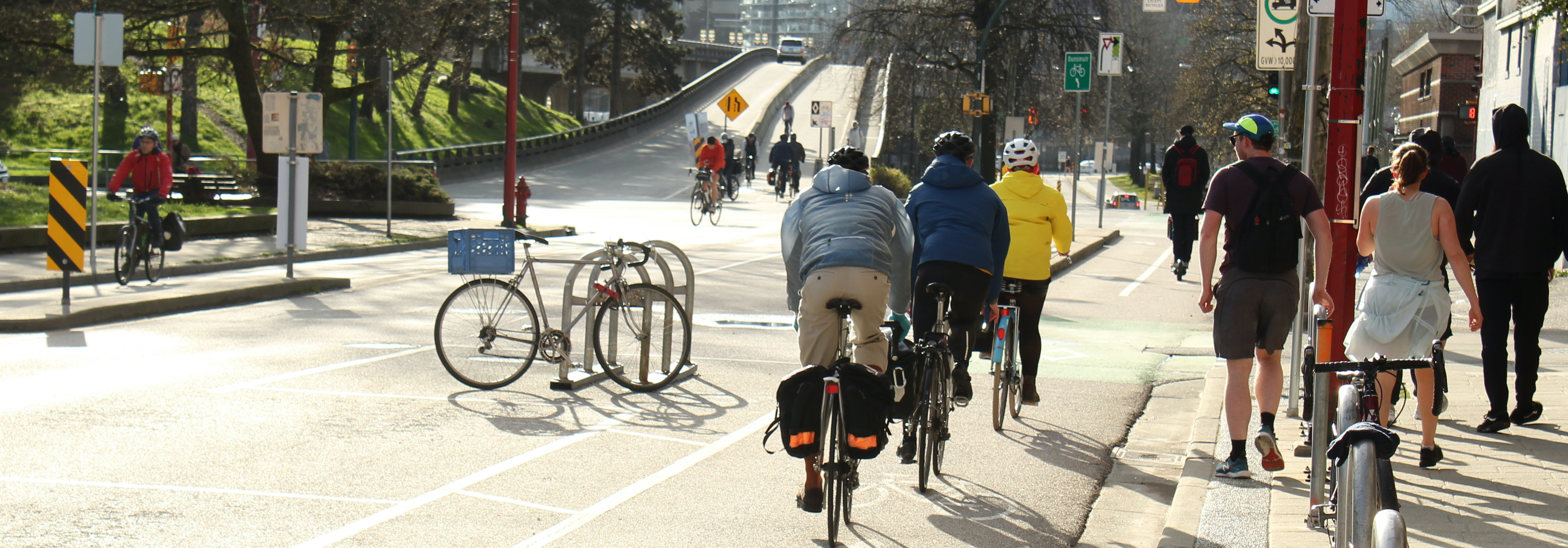 cyclists in bike lanes, pedestrians walking, road leading to a bridge