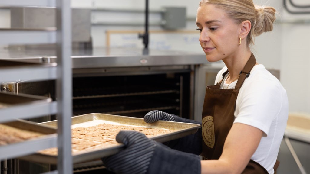 Woman taking baking sheets out of the oven to cool.