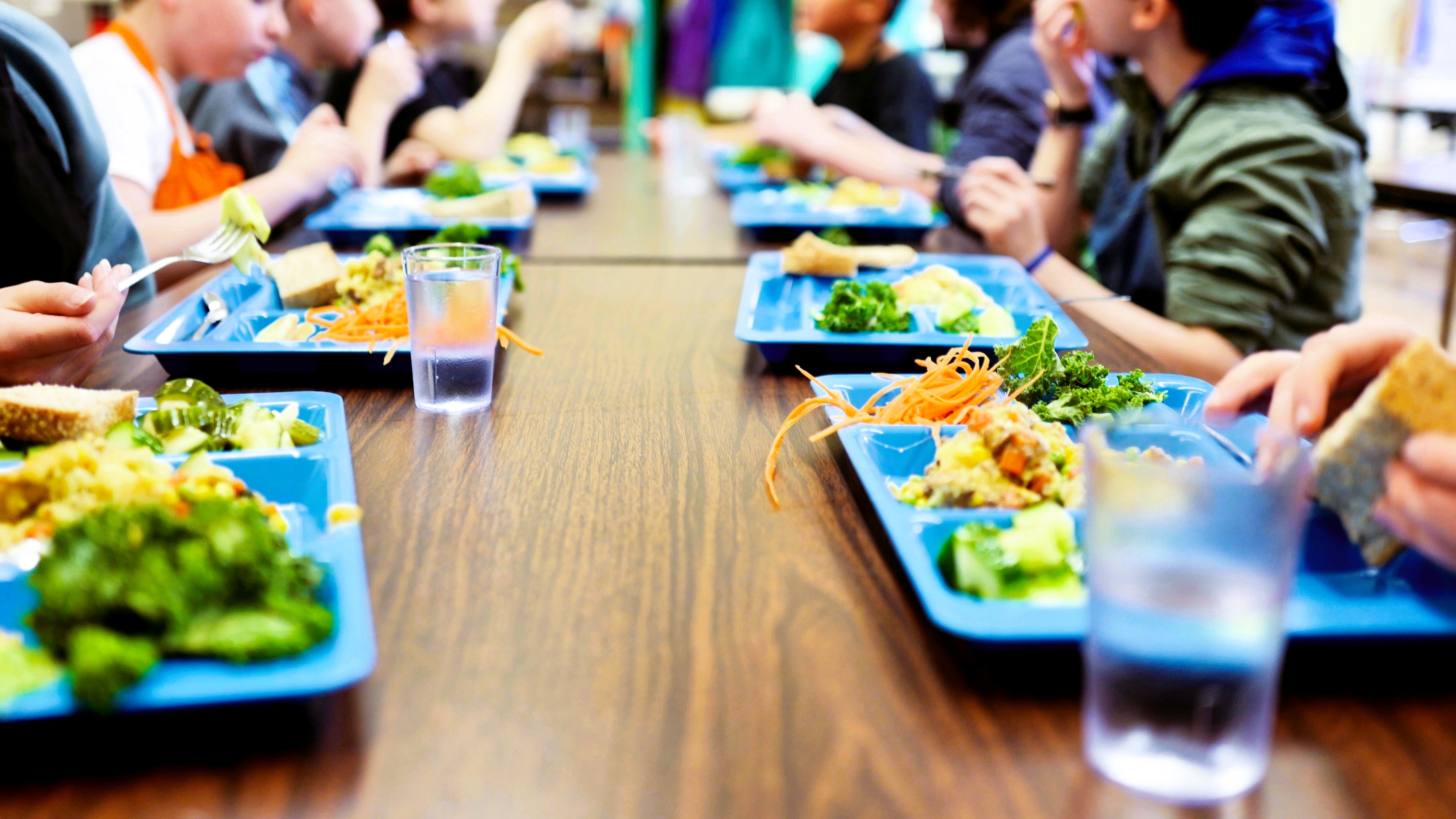 Kids sitting at a long table sharing a meal prepared at LunchLAB.