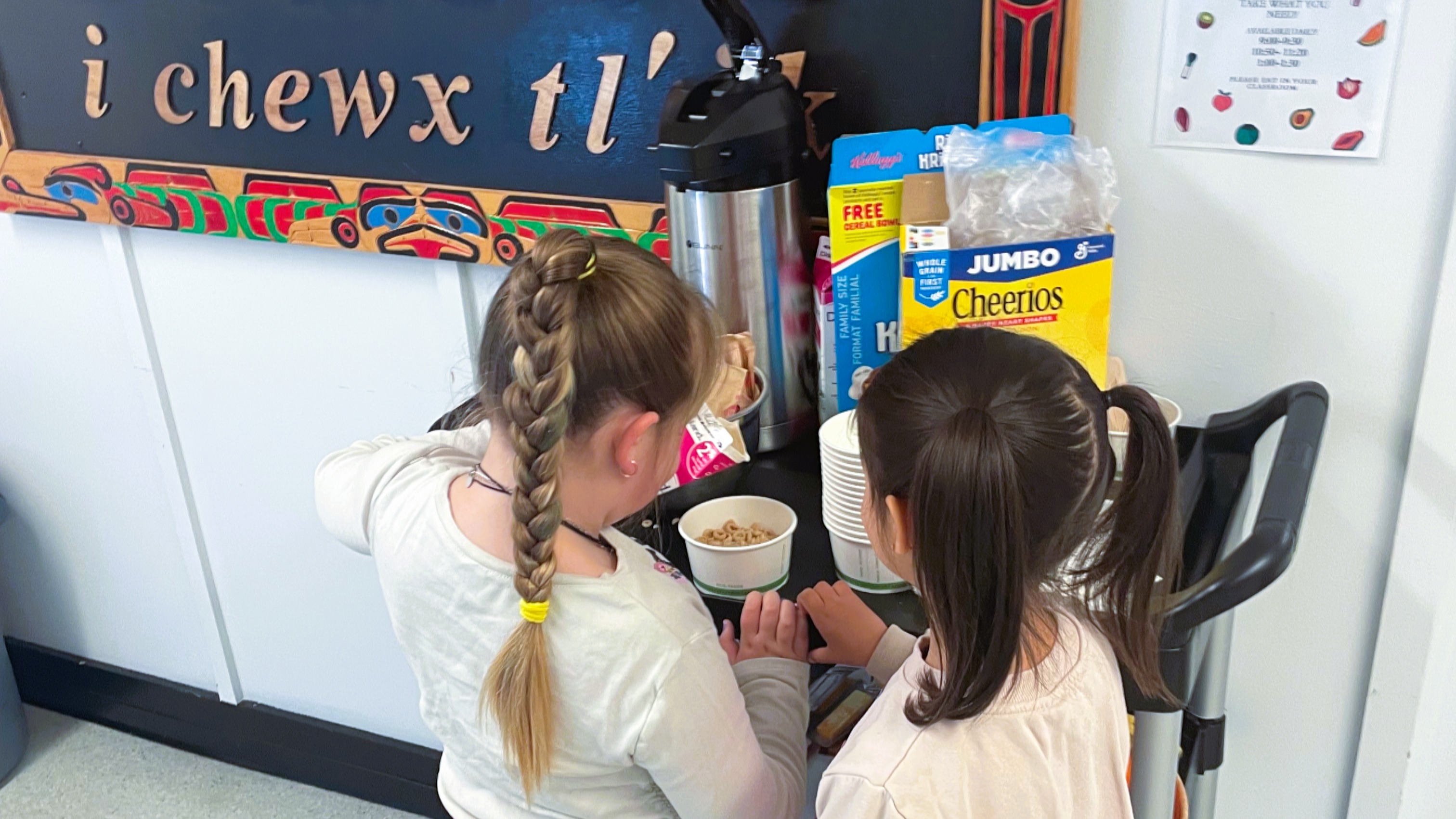 Two young girls serving themselves from a breakfast cart. 