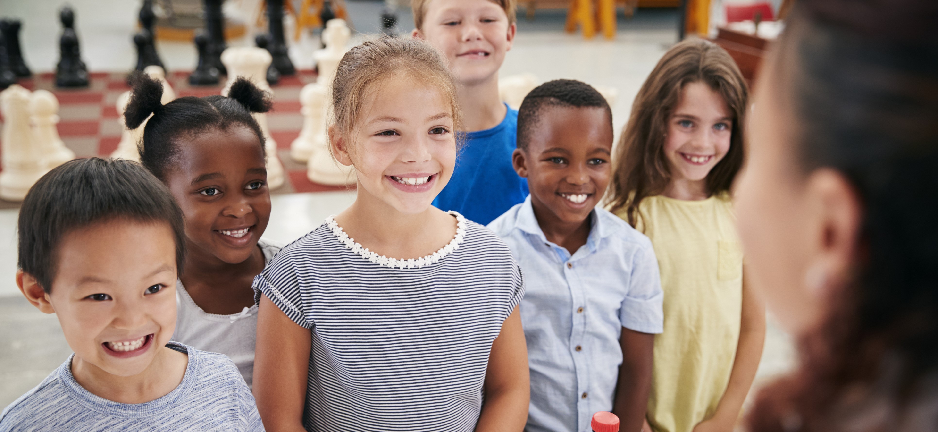 Group of smiling kids listening to teacher in classroom