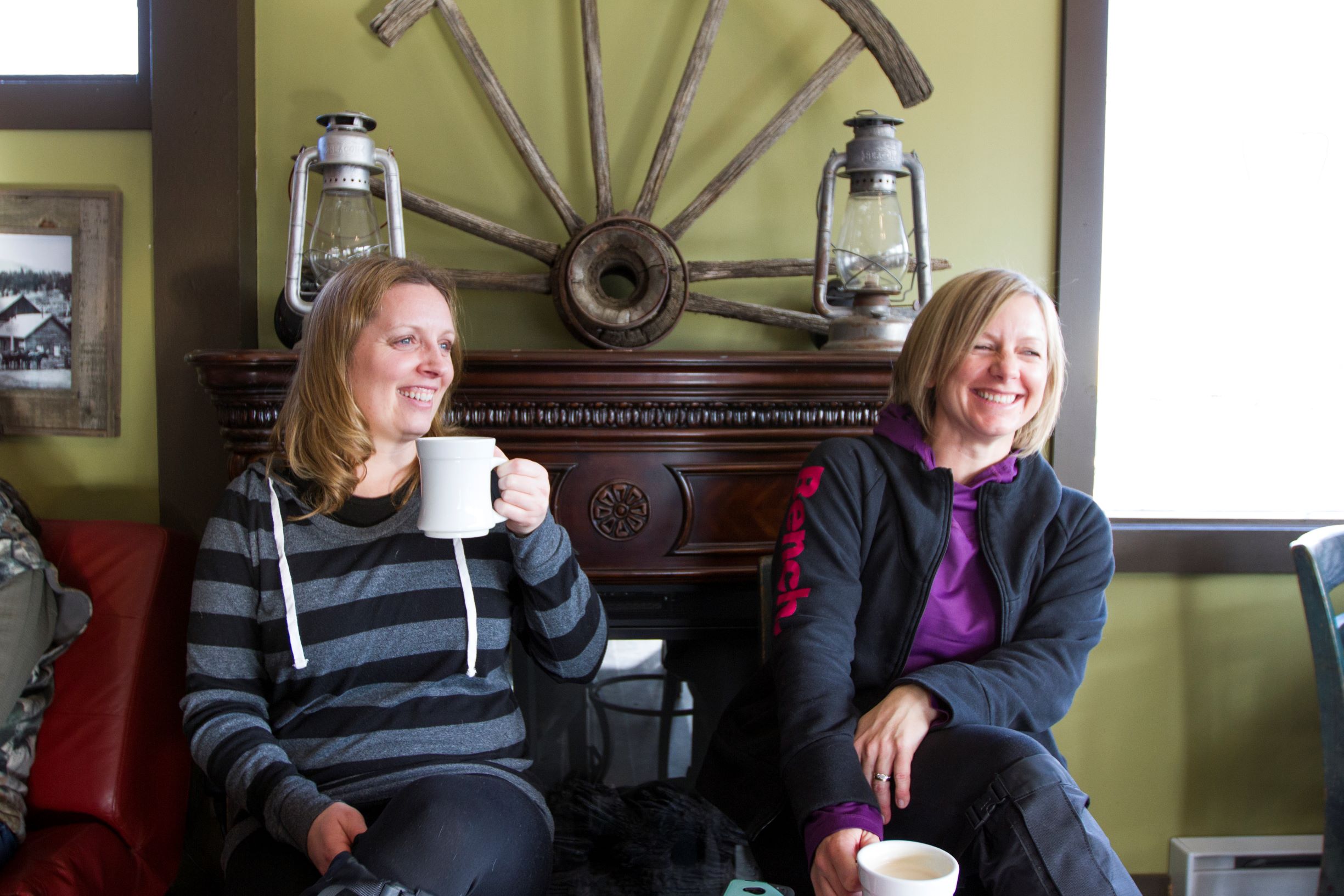Two women smiling and drinking coffee in a cafe 