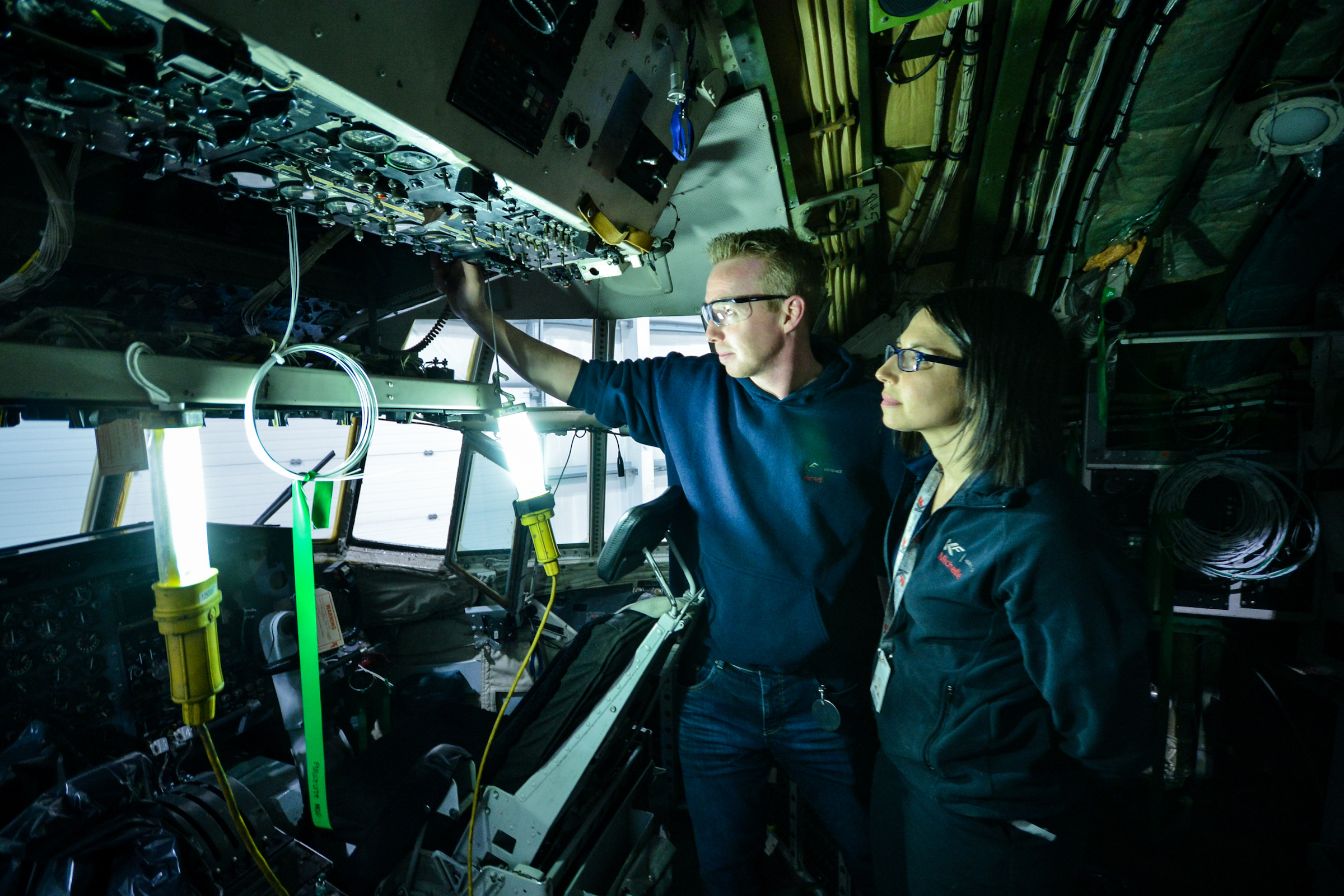 Two people working on the interior of an aircraft