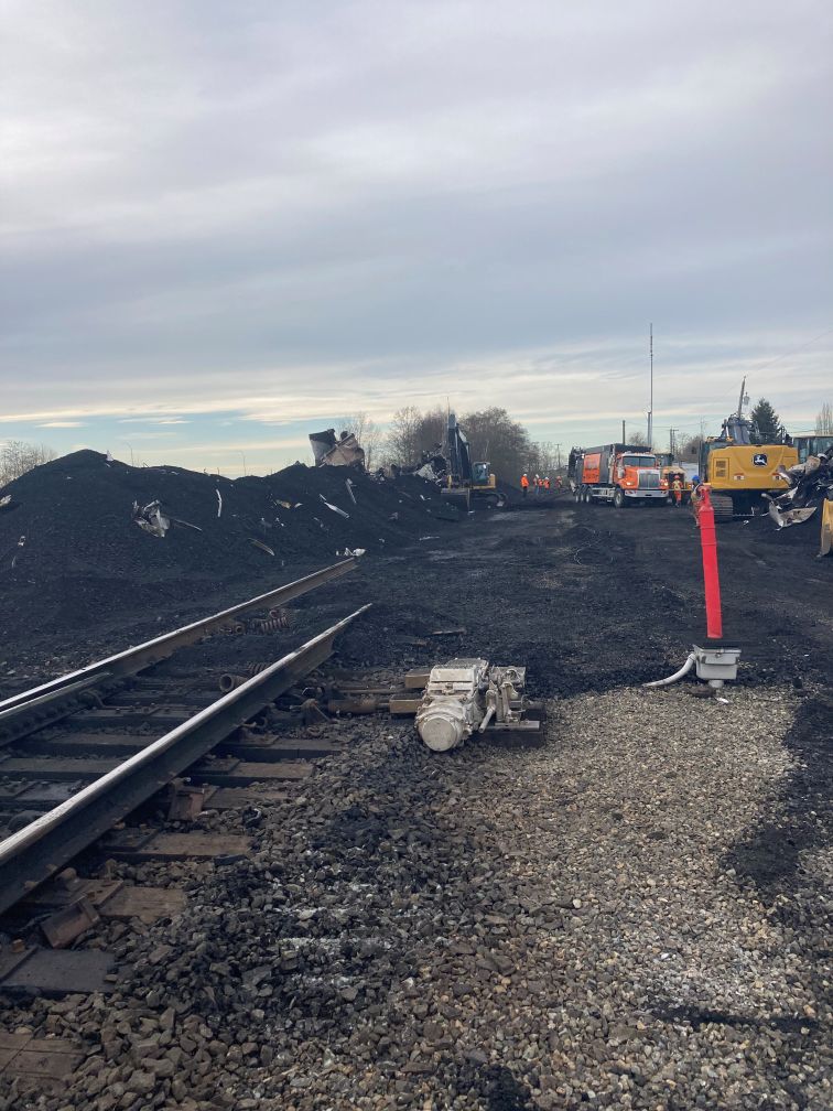 coal spilled on railway and heavy machinery in background