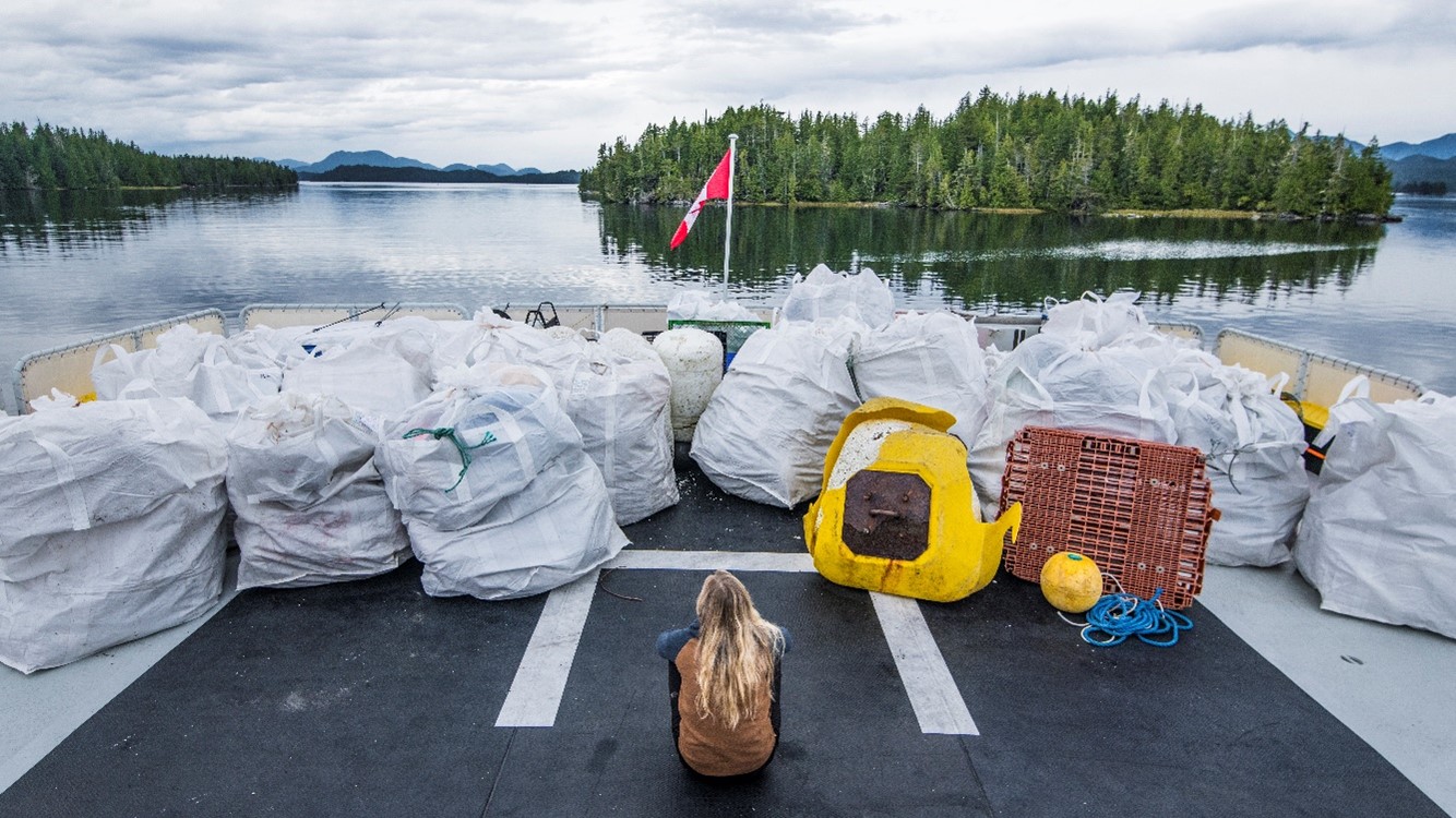 Person sitting on ship deck with bags of garbage