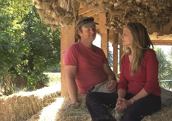 Couple sitting on hay bales discuss starting a new farm