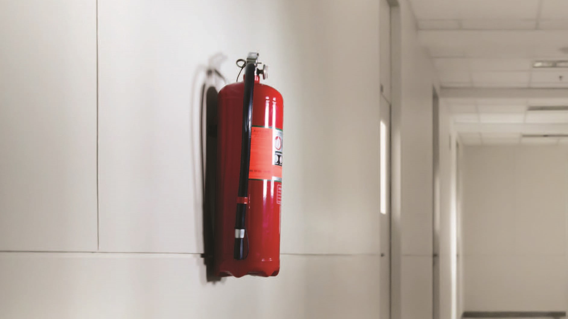 A  red fire hydrant attached to the wall