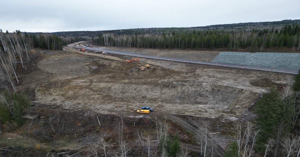 Aerial view of construction crews working to stabilize the slope alongside the affected section of highway.