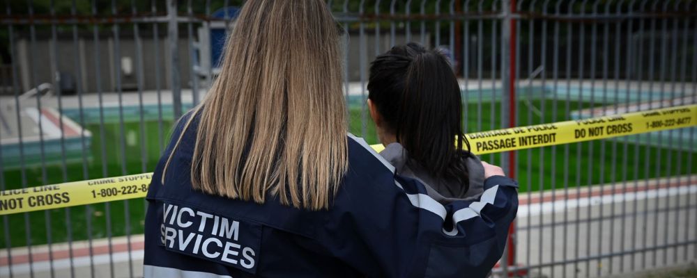 two people looking at closed off area wearing a jacket that says Victim Services