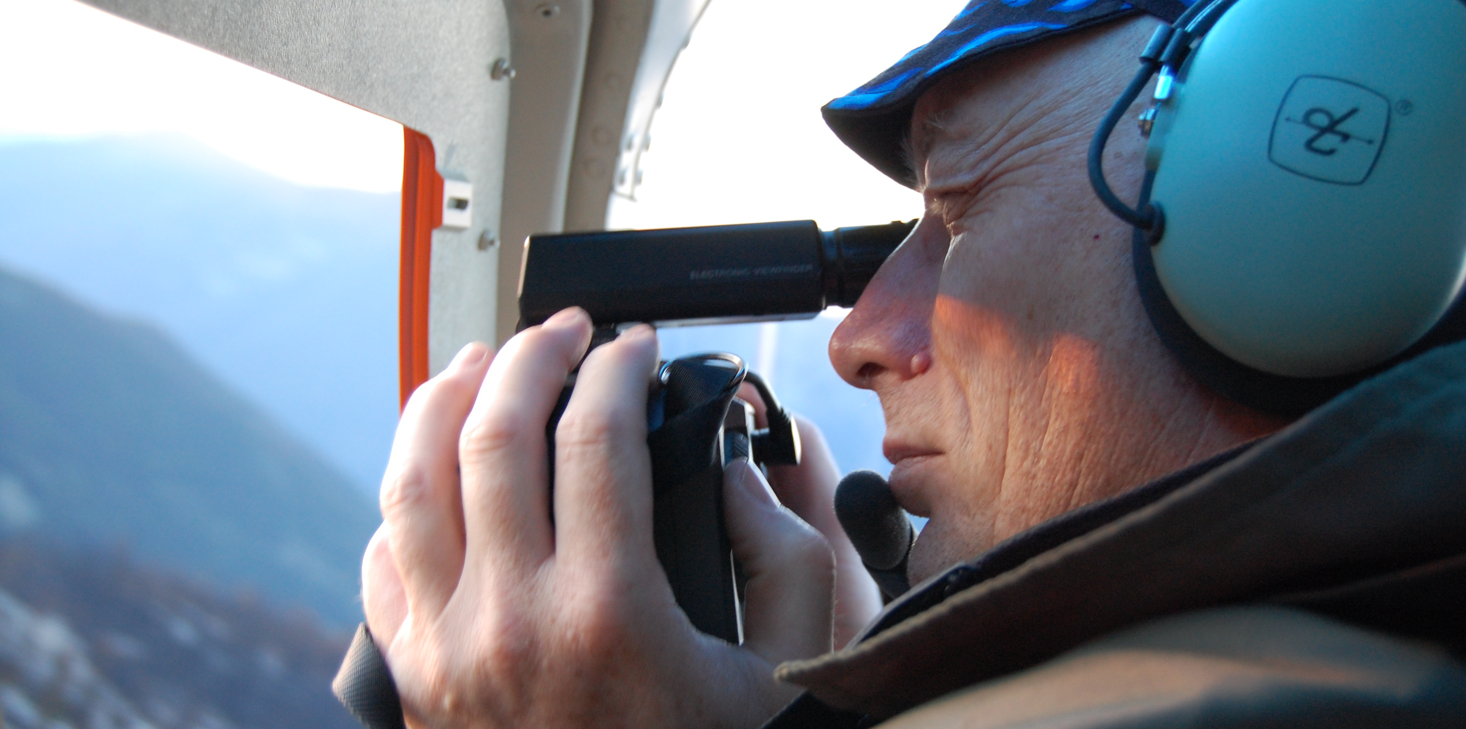 Man looks out airplane window to detect wildfires