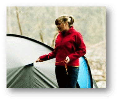 Woman zipping tent in recreation site