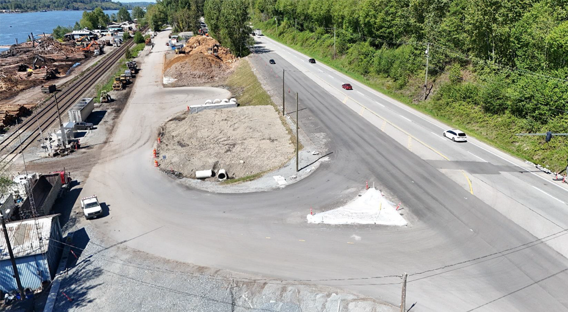 Aerial view of road paved road and train track winding through countryside.