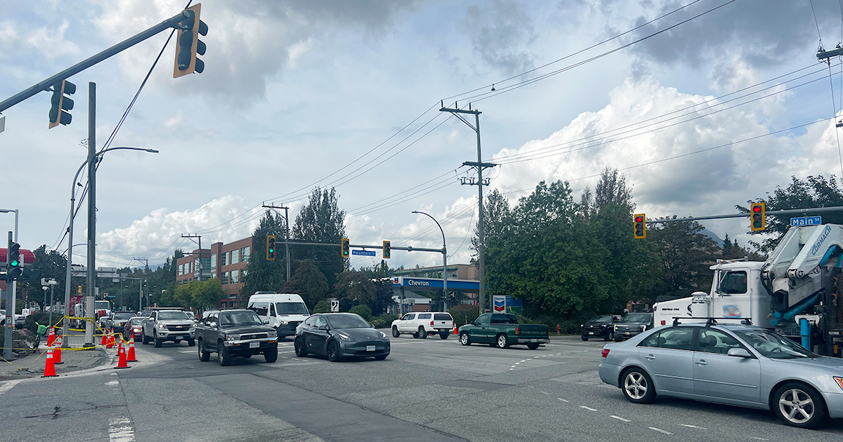 Busy intersection at Main Street and Mountain Highway in North Vancouver, showing rough asphalt and roadworks at the edges